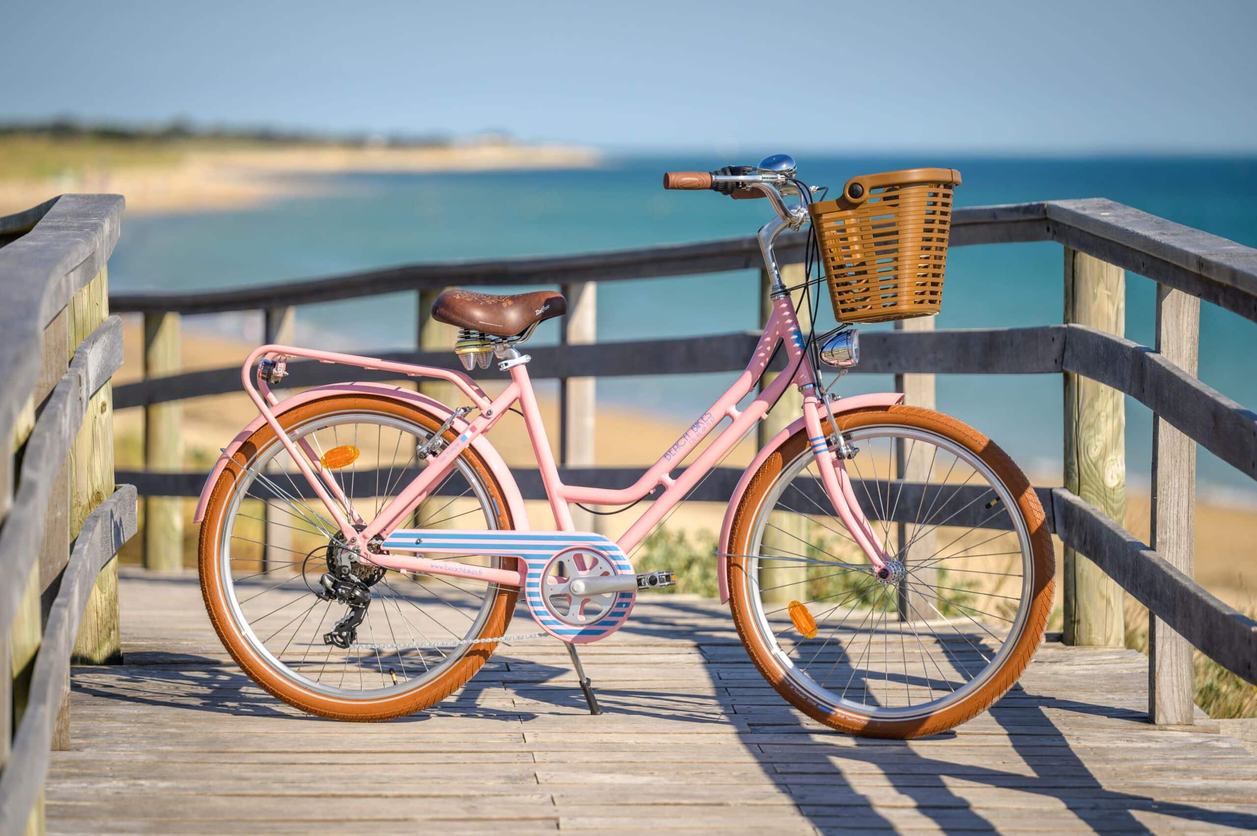 Vélo confort adulte rose devant la plage.