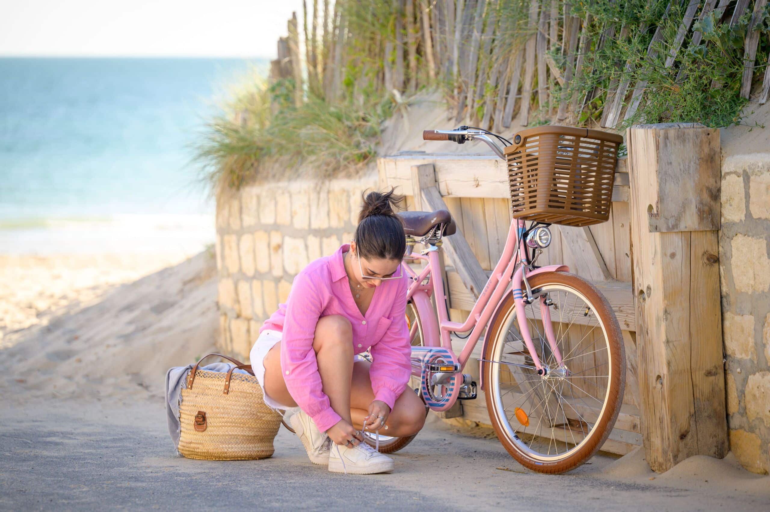 Touriste devant un vélo rose de location de la marque Beach Bikes.